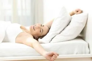 mujer durmiendo Importancia de dormir - Mujer despertando contenta