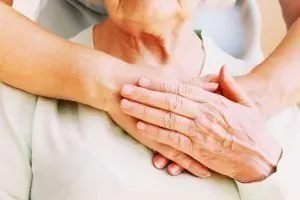 Depresión en la tercera edad - Anciana y persona joven agarradas de las manos