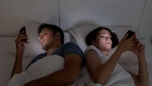 Pareja acostada con celulares