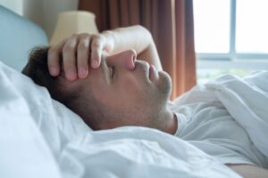 Migraña emocional - hombre en la cama con dolor