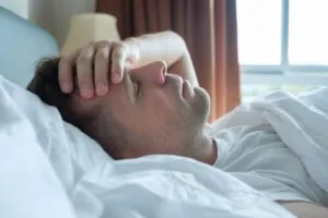 Migraña emocional - hombre en la cama con dolor