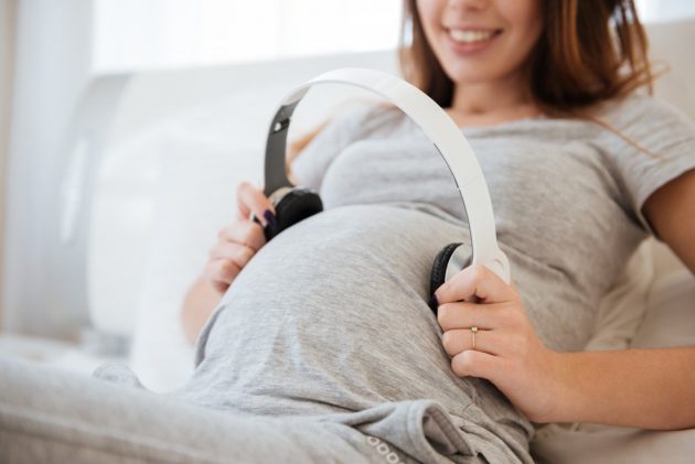 música durante el embarazo - mujer embarazada con auriculares en su panza